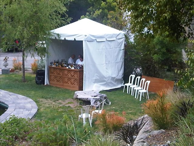 A white tent with chairs and tables in the grass.