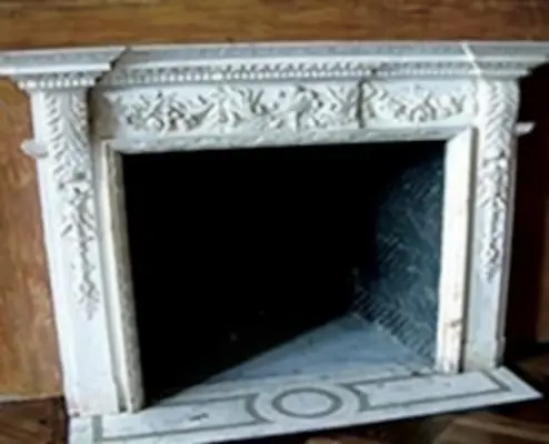A fireplace with a white marble surround and an ornate design.