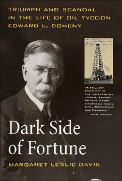 A man in glasses and suit standing next to an oil rig.