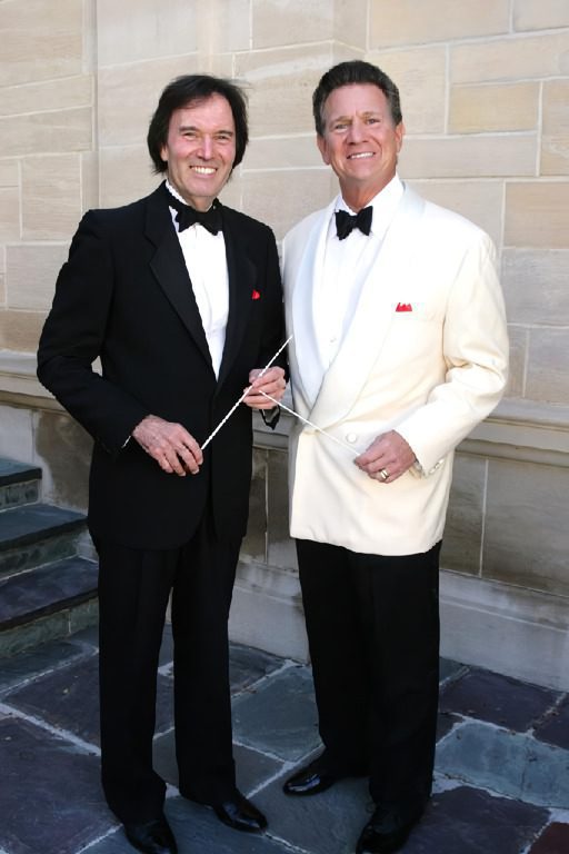Two men in tuxedos posing for a picture.
