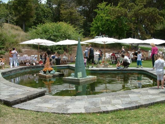 A fountain with people in it and umbrellas