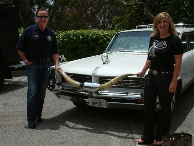 A man and woman standing next to an old car.