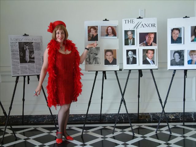 A woman in red dress standing next to several posters.